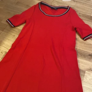 Röd klänning från Tommy Hilfiger helt ny  - Snygg röd klänning från Tommy Hilfiger, oanvänd. Klänningen har korta ärmar och en normal passform. Perfekt för en stilren look.