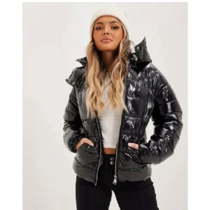 Svart glansig pufferjacka - Snygg svart glansig pufferjacka med dragkedja och hög krage. Perfekt för kyliga dagar med sin stilrena look och bekväma passform. Jackan har långa ärmar och praktiska fickor framtill. Ifrån Nelly i storlek M men sitter mer som en S. Nypris 700, mitt pris 400!