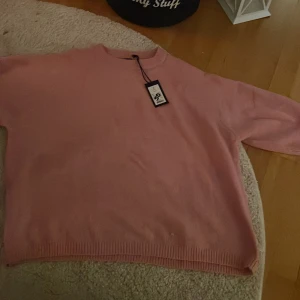 Rosa stickad tröja - Säljer en söt rosa stickad tröja med rund hals och trekvartsärmar. Perfekt för en avslappnad stil och passar bra till jeans. Tröjan har en mjuk och bekväm känsla. Ny med prislapp men köptes på rea. 