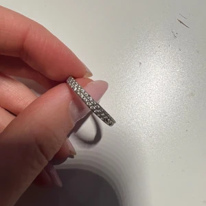 Glittrig silverring - Elegant och stilren silverring med glittrande stenar runt om. Perfekt för att ge en extra touch av glamour till din look. Passar både till vardag och speciella tillfällen.