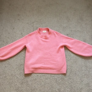 Rosa stickad tröja från Soft Goat - Mysig rosa stickad tröja från Soft Goat. Storlek m. Köpt för ca 2000. Tröjan är i en härlig rosa nyans som ger en färgklick till garderoben.