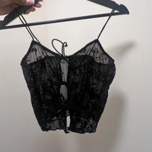 Svart spetslinne - Snyggt svart spetslinne med tunna axelband och knytning framtill. Perfekt för utekvällar eller för date night 