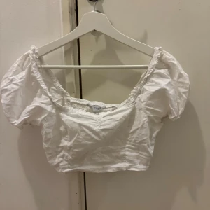 Vit croppad blus - Söt vit croppad blus med puffiga kortärmar och elastisk halsringning. Perfekt för en somrig look.