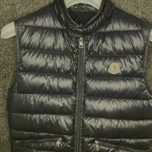 dunväst från Moncler - Snygg marinblå dunväst från moncler Perfekt till kallare dagar när du vill hålla stilen. Storlek 2 vilket motsvarar S/M.                    Köpt från luxariosecret som bara säljer äkta varor. Pris går att diskutera och är även öppen för byten!