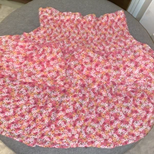 Blommig kjol från ONLY - Söt blommig volang  kjol från ONLY i rosa och vita nyanser. Kjolen har en smockad överdel och volangdetaljer som ger en romantisk känsla. Perfekt för sommarens varma dagar. Storlek L men sitter som S