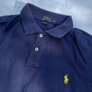 Polo Ralph Lauren piké blå - Sällan använd och bra skick. Polo Ralph Lauren piké för för barn (S/P). Gul häst. Säljer den för lågt pris. Först till kvarn!                        Butik pris: 899kr