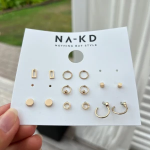 Örhängen - En karta med örhängen från NA-KD. 7 av 9 par kvar (vet ej var de resterande 2 tagit vägen) Gjorda av mässing, glas och stål.  (ALDRIG ANVÄNDA)