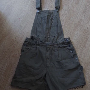 Gröna hängselshorts/Snickarbyxor - Gröna hängselshorts/snickarbyxor, tidigare köpt secondhand, på beyond retro stockholm. Storlek M, justerbara hängslen, bekväma och stilrena.