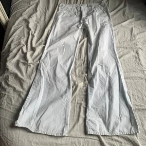Vita Lågmidjade utsvängda byxor - Vita Lågmidjade utsvängda byxor från märket Lucky Brand. Fint skick, 100% bomull. Midjemått 40cm mätt rakt över och innerbenslängd 82cm. 