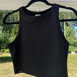 Svart linne - Ett svart croppat linne från H&M. Inköpt för ett antal år sedan men användes aldrig tyvärr. Passar bra till mig som normalt har S i toppar ☺️  (ALDRIG ANVÄND)  Längd: 40 cm Axel: 25 cm