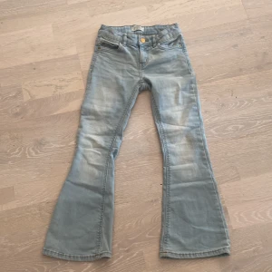 Ljusblå utsvängda jeans - Ett par fina tjejjeans som är jeans märket detroit men köpta på Lindex. Dom här byxorna är utsvängda där nere och är storlek 128 7-8 år!
