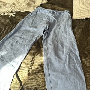 Ljusblå linnebyxor med resårmidja - Säljer ett par ljusblå linnebyxor som är perfekta för sommaren. De har en bekväm resårmidja och en avslappnad passform. Byxorna är i ett mjukt och luftigt material, vilket gör dem idealiska för varma dagar. Perfekta för en avslappnad stil eller en dag på stranden!