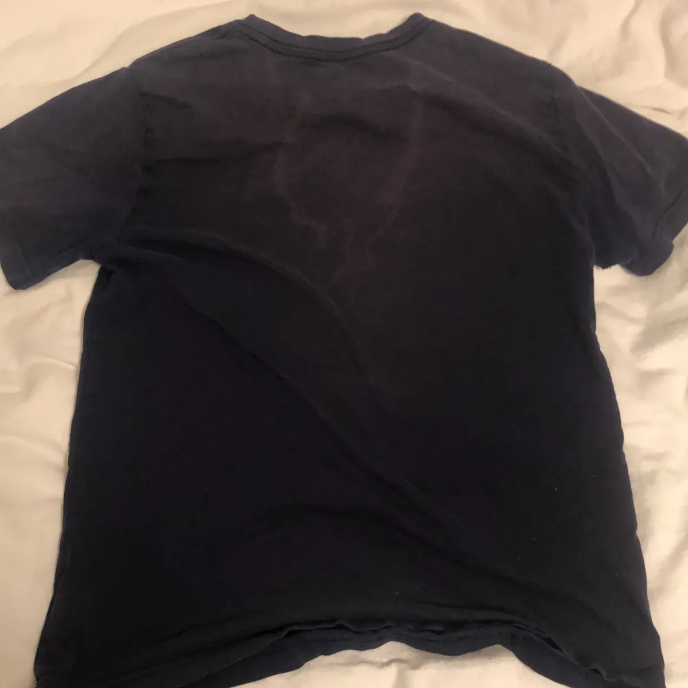 Säljer en snygg mörkblå t-shirt från Polo Ralph Lauren. Den har en liten röd broderad logga på bröstet och är i bra skick. Perfekt för en casual look!. T-shirts.