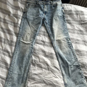 Ljusblå jeans från Smog - Säljer ett par ljusblå jeans från Smog i storlek 36/34. De har en klassisk femficksdesign och en snygg tvättad look. Perfekta för vardagsbruk och kan enkelt matchas med olika outfits. Passar bra för både vår och sommar.