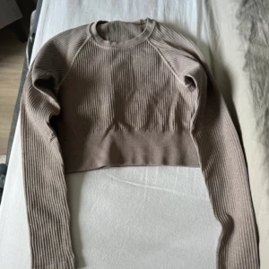 Beige ribbad croppad tröja och byxor - Säljer ett underställset med en beige ribbad croppad tröja och matchande byxor. Tröjan har långa ärmar och byxorna är i samma ribbade material. Perfekt för en avslappnad utflykt. Observera att det finns en liten defekt på byxorna, se bild. Passa på att fynda detta set!