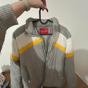 Grå pufferjacka från Guess - Säljer en grå lätt puffar jacka från Guess som köptes för flera år sen. Användes bara 1 gång. Storlek L eller 44