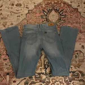 Ljusblå jeans från Lee - Säljer ett par ljusblå lågmidjade bootcut jeans från Lee i modellen Joliet. Perfekta för både vardag och fest! Midjemått: 33cm, innerbenslängd: 80cm, lårmått: 17cm, ankelmått: 19cm skriv för fler bilder