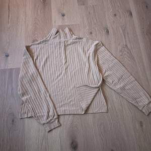 Säljer en supermysig beige polotröja i ribbat material. Perfekt för höst och vinter med sin långa ärmar och höga krage. Tröjan har en lös passform som gör den extra bekväm att bära. Passar perfekt till både jeans och kjol!