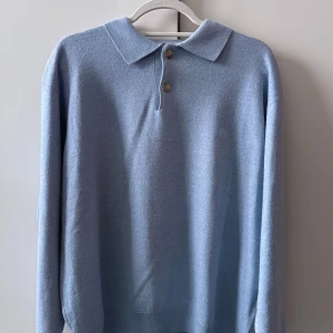 Ljusblå polotröja från Burberry - Säljer en elegant ljusblå polotröja från Burberry i mycket bra skick. Perfekt för både höst och vår, och funkar lika bra till vardags som till lite finare tillfällen.