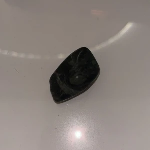 Svart polerad sten - En liten, svart polerad sten med en slät yta och subtila mönster. Perfekt som dekoration eller för samlingar. Stenen har en elegant och mystisk känsla.