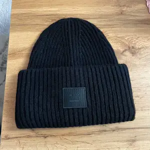 Hej! Säljer en svart stickad mössa från Acne Studios i mycket bra skick. Den är ribbad och har en stilren design med en liten logotyp framtill. Perfekt för att hålla sig varm under höst och vinter!