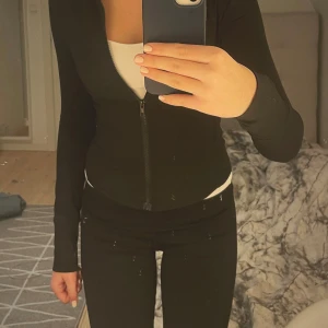 Svart tight träningsjacka med dragkedja - Säljer en svart tight jacka i mycket bra skick. Den har en dragkedja framtill och är långärmad. Perfekt för för träning men funkar även till vardags. Enkel och stilren design som passar till det mesta.😍 Storlek S men passar Xxs-s (liten i storlek)