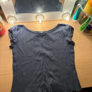 Mörkblå ribbad topp från 157💙 - Säljer en mörkblå ribbad topp från 157 i storlek S. Toppen har korta ärmar med en söt volangdetalj vid ärmsluten. Perfekt för både vardag och festliga tillfällen. Den är i bra skick och redo för en ny ägare! Köp👌🏼😍!