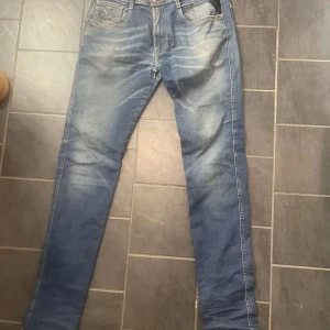 Blå jeans från Replay - Säljer ett par snygga blå jeans från Replay i modellen Anbass. De har en slim passform och är i bra skick med en cool tvättad look.  Har däremot lite slitningar i skrevet. Perfekta för både vardag och fest! 🕺