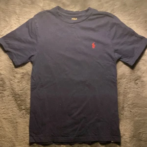 Mörkblå t-shirt från Polo Ralph Lauren - Säljer en mörkblå t-shirt från Ralph Lauren i storleken 10-12 som är runt 162 skulle jag säga! Den ganska använd men har inga fläckar vad jag har sett! Skriv för fler bilder eller frågor och funderingar!