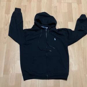 Svart hoodie från Polo Ralph Lauren - Säljer en svart hoodie från Polo Ralph Lauren i mycket bra skick. Storlek L men passar bäst som M/L använd någon gång men mest legat i garderoben skriv om ni undrar något 