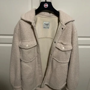 Beige teddyjacka från Abercrombie & Fitch - Mysig beige teddyjacka från Abercrombie & Fitch i storlek XS. Perfekt för höst och vinter med sin fluffiga och varma design. Jackan har långa ärmar och knappar framtill, samt två stora fickor på bröstet. Superfin och i mycket bra skick!