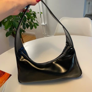 Svart axelväska i syntetmaterial Carin Wester - Snygg svart axelväska från Carin Wester. Perfekt för både vardag och festliga tillfällen. Liten defekt på axelremmen som säkert går att fixa, annars superfint skick💖 köparen betalar frakten. 📦