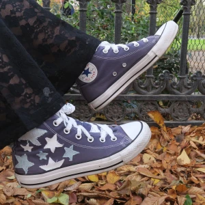 Lila sneakers med stjärnmönster - Säljer ett par coola lila sneakers med vita stjärnor och klassisk snörning med spetssnören. Perfekta för hösten med sin unika stil och bekväm. De har en vit sula och är i mycket bra skick. Passar perfekt för en avslappnad dag i parken eller en promenad i stan.