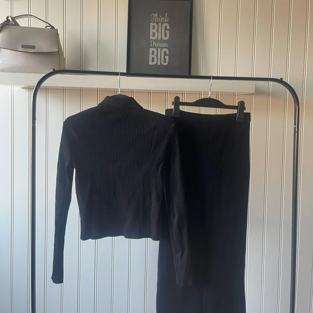 Snygg svart ribbad kjol med knappar framtill. Perfekt för både vardag och fest. Kjolen är i ett stretchigt material som ger en bekväm passform. Matcha med en stilren topp för en komplett look!. Hameet.