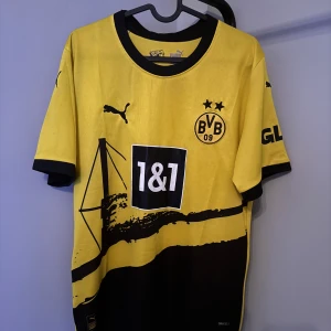 Gul och svart Borussia Dortmund fotbollströja - Säljer en snygg gul och svart Borussia Dortmund fotbollströja från Puma. Den har korta ärmar och klubbens logga på bröstet. Perfekt för alla BVB-fans! 🖤💛 självklart äkta nypris 1199 mitt pris 329