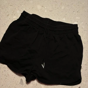 Svarta shorts från H&M - Säljer ett par svarta shorts från H&M i storlek M. De är i bra skick och har en bekväm resårmidja med snörning. Perfekta för en avslappnad dag eller träning. 🖤