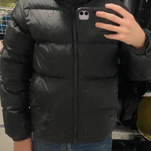 Svart pufferjacka från Tommy Hilfiger - Säljer en svart pufferjacka från Tommy Hilfiger bra skick! Pris går att diskuteras. Jackan är inte smutsig utan spegeln. Storlek 164-170