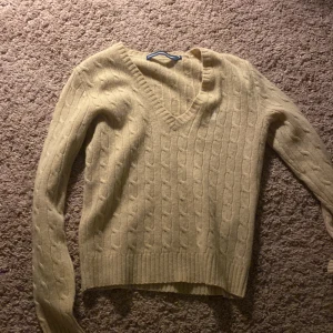 Beige kabelstickad tröja från Ralph Lauren Sport - Säljer en snygg beige kabelstickad tröja från Ralph Lauren Sport. Den har en v-ringad hals och långa ärmar, perfekt för höst och vinter. Tröjan är i bra skick och passar både till vardags och lite finare tillfällen. Supermysig och stilren! 🍂