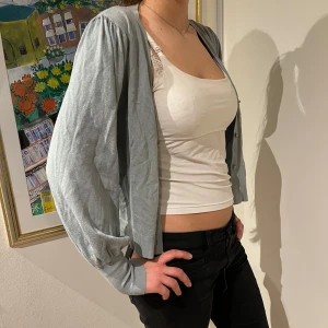 Ljusgrå kofta - Säljer en ljusgrå kofta i mjukt material. Den har långa ärmar med en lätt puffig stil och ribbade muddar. Perfekt för lager-på-lager under hösten eller våren. Enkel att matcha med olika outfits!