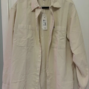 Beige overshirt från Wrangler - M - Säljer en snygg beige overshirt från Wrangler i nytt skick (med tags). Den har en klassisk krage och knappar hela vägen ner. Två praktiska bröstfickor ger en cool look. Perfekt för lager-på-lager-stil under hösten eller våren. Passar både till vardags och lite mer uppklädda tillfällen. Storlek medium men är rätt stor i storleken. Nypris ca: 700 kr