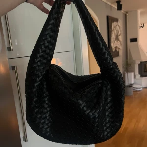 Svart flätad axelväska från NA-KD - Säljer en superfin svart flätad axelväska från NA-KD. Väskan är i mycket bra skick och har ett huvudfack med en dragkedjestängning och ett innerfack med en dragkedjestängning. Perfekt för både vardag och fest! 🖤