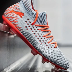 Grå och orange fotbollsskor från Puma - Säljer ett par gråa och orangea fotbollsskor från Puma i  bra skick. Skorna har en snygg stickad design med orange snörning och en slitstark sula med dobbar för bra grepp på planen. Perfekta för fotbollsträning och matcher!