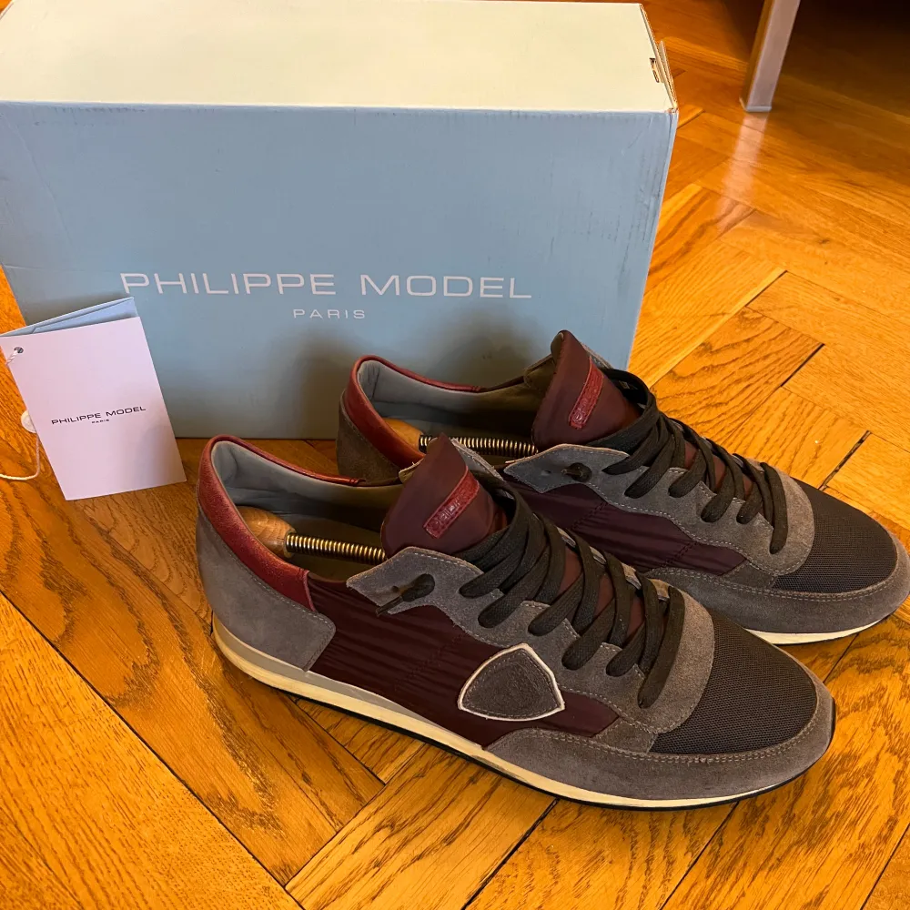 Snygga Philippe Model sneakers i grått och vinrött. De har en stilren design med snörning och en bekväm sula. Perfekta för både vardag och fest. Skorna är i mycket bra skick och kommer med originalkartong.. Skor.