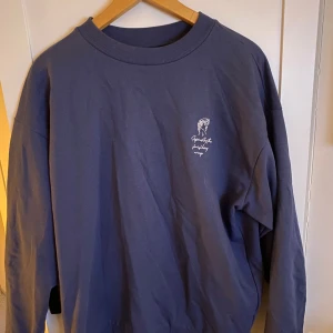 Mörkblå sweatshirt Lager 157  - Säljer en snygg mörkblå sweatshirt med ett stilrent tryck på bröstet. Tröjan har en rund halsringning och långa ärmar, perfekt för en avslappnad stil. Materialet känns mjukt och bekvämt, idealiskt för både vardag och mysiga stunder hemma.