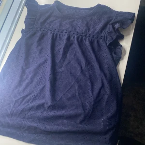 Mörkblå blus med spetsdetaljer - Säljer en söt mörkblå blus med spetsdetaljer och volangärmar. Perfekt för både vardag och fest! Blusen har en luftig passform och är i mycket bra skick.