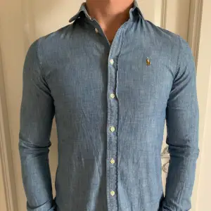 Säljer en snygg blå skjorta från Polo Ralph Lauren i mycket bra skick. Det är storlek 4, men den sitter som S. Som referens är killen på bilden 180 o väger 70kg. Den är perfekt för både vardag och festliga tillfällen. Den är tillverkad i ett mjukt och bekvämt material som känns skönt mot huden. Passar perfekt till jeans eller chinos för en stilren look. 