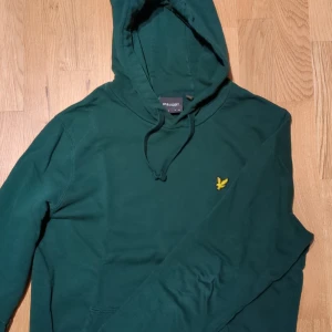Grön hoodie från Lyle & Scott - Säljer en snygg grön hoodie från Lyle & Scott i storlek M. Den har en klassisk design med en gul logotyp på bröstet och justerbar huva. Perfekt för både vardag och chill. Skön och stilren, ett måste i garderoben! 💚 300 kr men kan förhandlas!