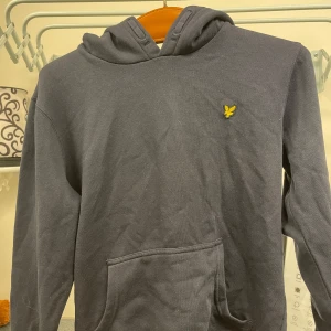 Mörkblå hoodie från lyle and scott - Säljer en snygg mörkblå hoodie från Lyle and scott i storlek 14/15 y(passar även lite mindre än S) Perfekt för höst och vinter med sin huva och praktiska ficka framtill. Passar både till alla tillfällen. Hör av dig vid intresse!