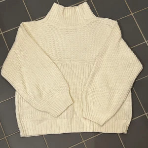 Vit stickad tröja från Monki - Säljer en mysig vit stickad tröja från Monki. Tröjan har en hög krage och långa ärmar med ribbade muddar. Perfekt för kyliga dagar och ger en stilren look. Passar bra till både jeans och kjol. 🧶✨