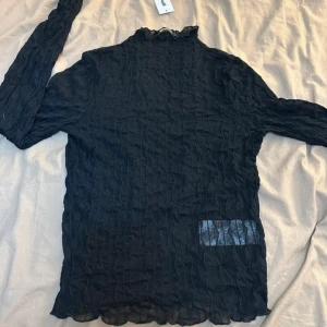 Svart långärmad topp med krage - Snygg svart långärmad topp med unik textur och hög krage. 